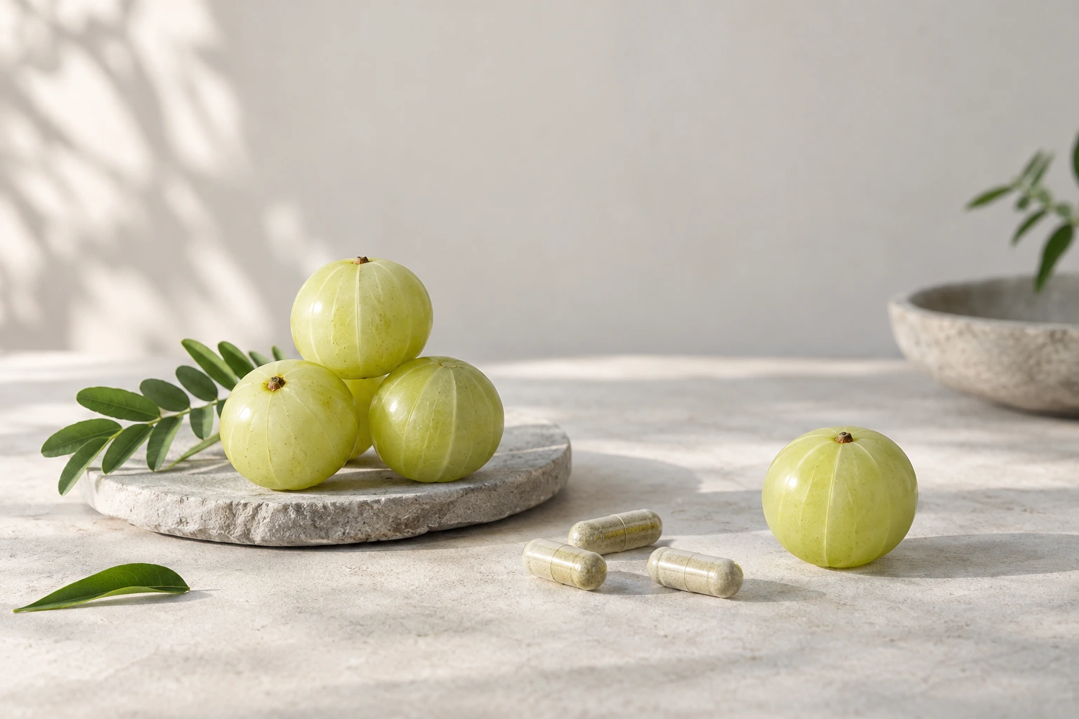 Fresh amla (Indian gooseberry) fruits beside a few plain capsules on a warm linen surface in soft daylight — ingredient still life for an article about amla capsules.